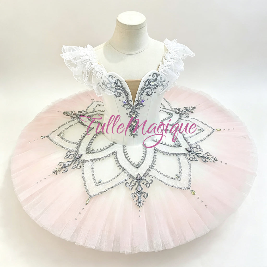 A light pink tutu features a white lace-trimmed bodice with silver embroidered details, a V-neckline, and a voluminous light pink tulle skirt.Professional classical ballet tutu for Crystal Fountain Fairy variation in Sleeping Beauty