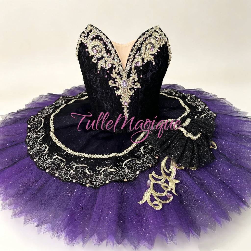Detailed look at a premium dark violet and black ballet stage costume for Satanella variation, showcasing gold appliques, purple crystal accents, and a stiff platter skirt plate.