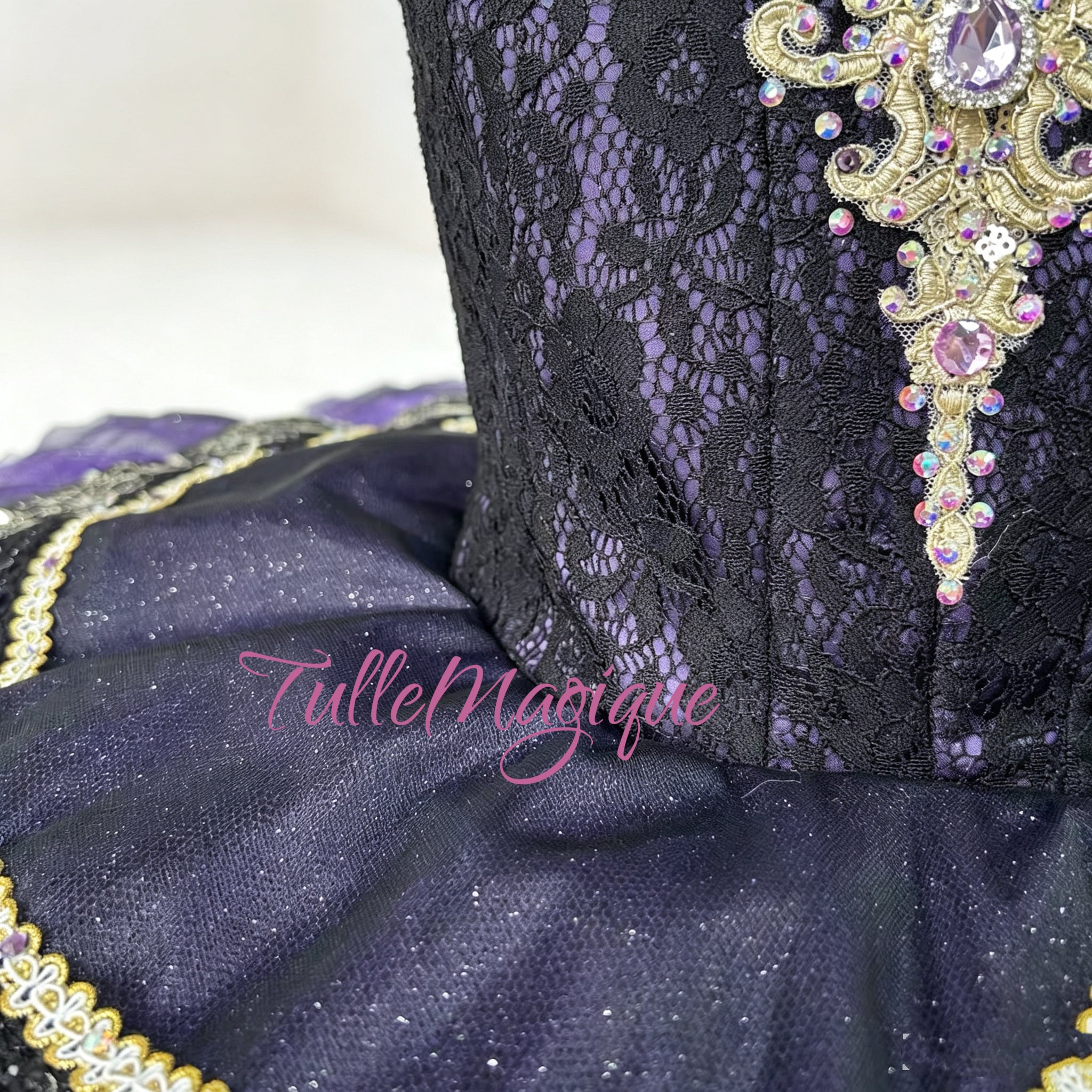 Professional deep purple classical ballet tutu for Raymonda Act 3 variation, featuring a black lace bodice with intricate gold Baroque embroidery and a tiered violet pancake skirt for YAGP.