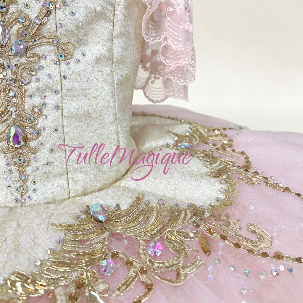 Detailed view of delicate lace sleeves on a professional pink and gold stage tutu for princess Aurora.