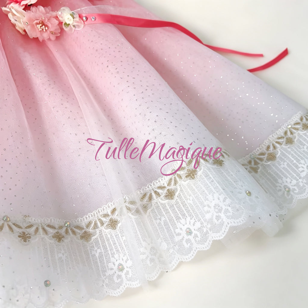 Detailed view of the pink and white gradient glitter tulle skirt displaying parallel silver trimmings, a wide white lace hemline, and a matching pink and white rose floral crown accessory.
