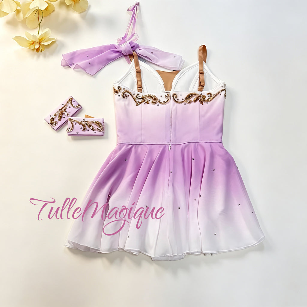 Greek style ballet tunic for Cupid variation in soft violet-pink gradient, showcasing a detailed bodice with cross-body gold scrollwork, matching detachable arm bands, and a fluid double-gradient skirt.