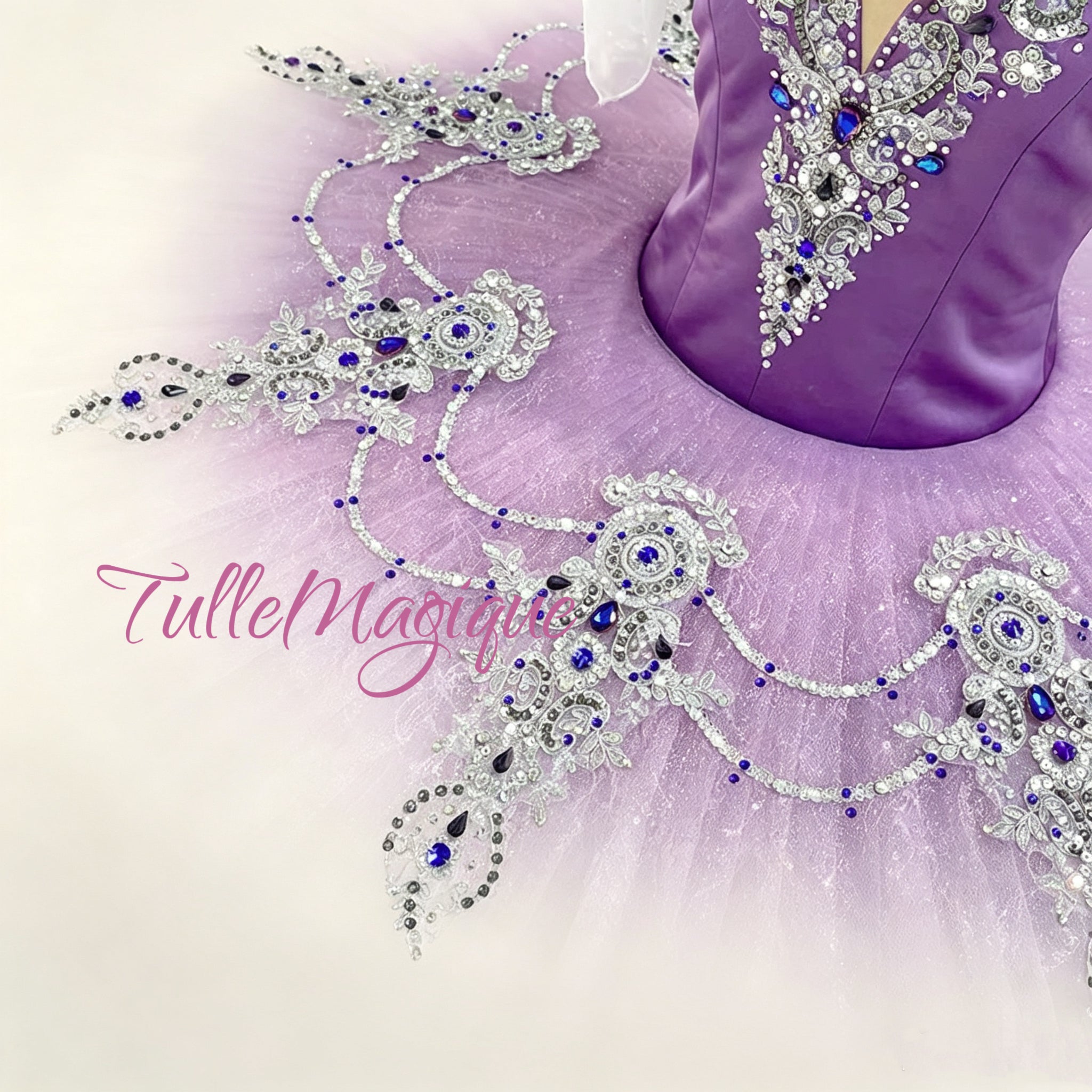 A close-up of a lavender tutu skirt with elaborate silver rhinestone embellishments and blue jewel accents, shown on a mannequin against a light background. 