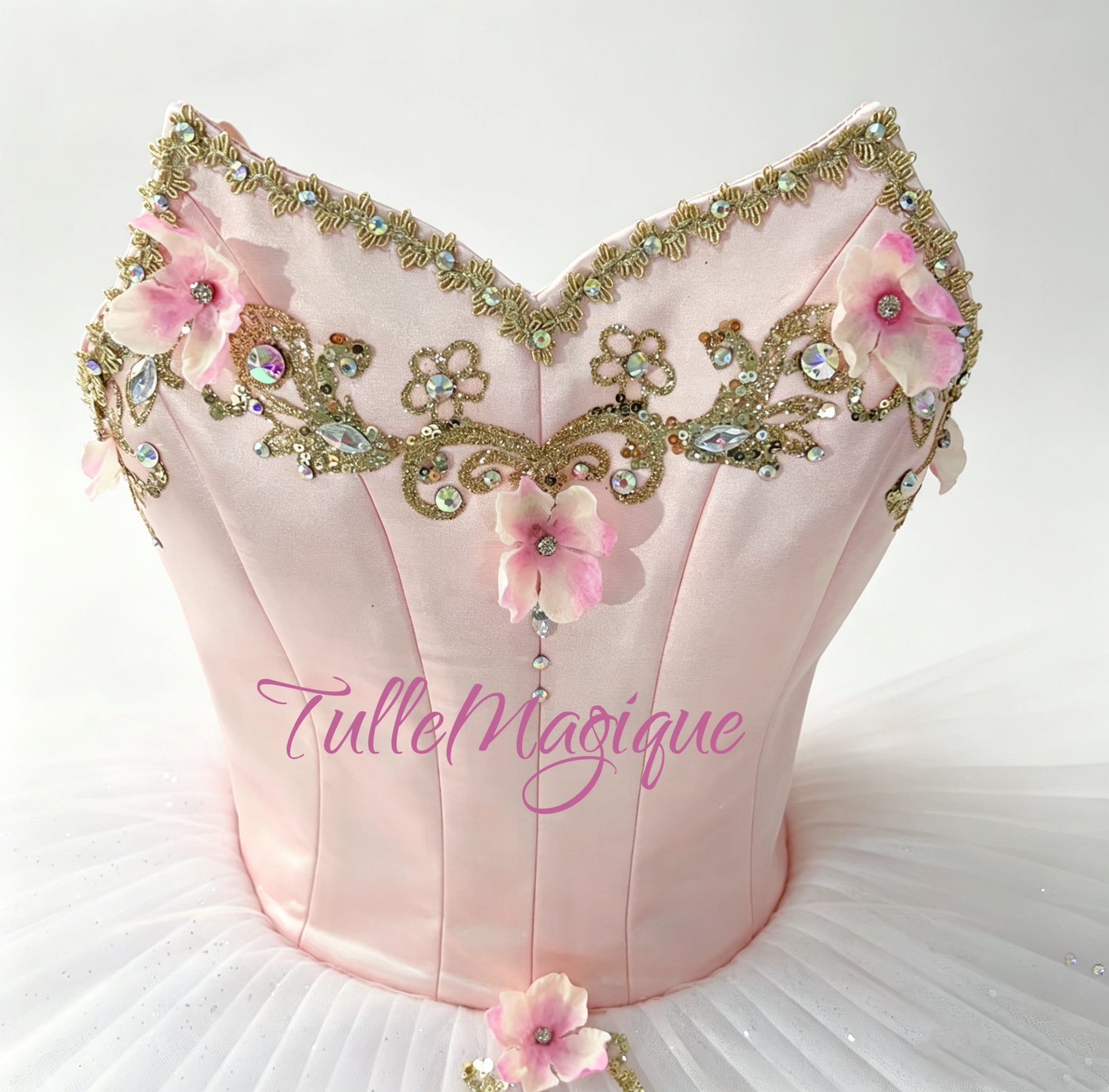 Close-up of a luxury pink and gold professional ballet competition tutu, showcasing a structured bodice with sweetheart neckline and shimmering rhinestone details and pink 3D flowers.