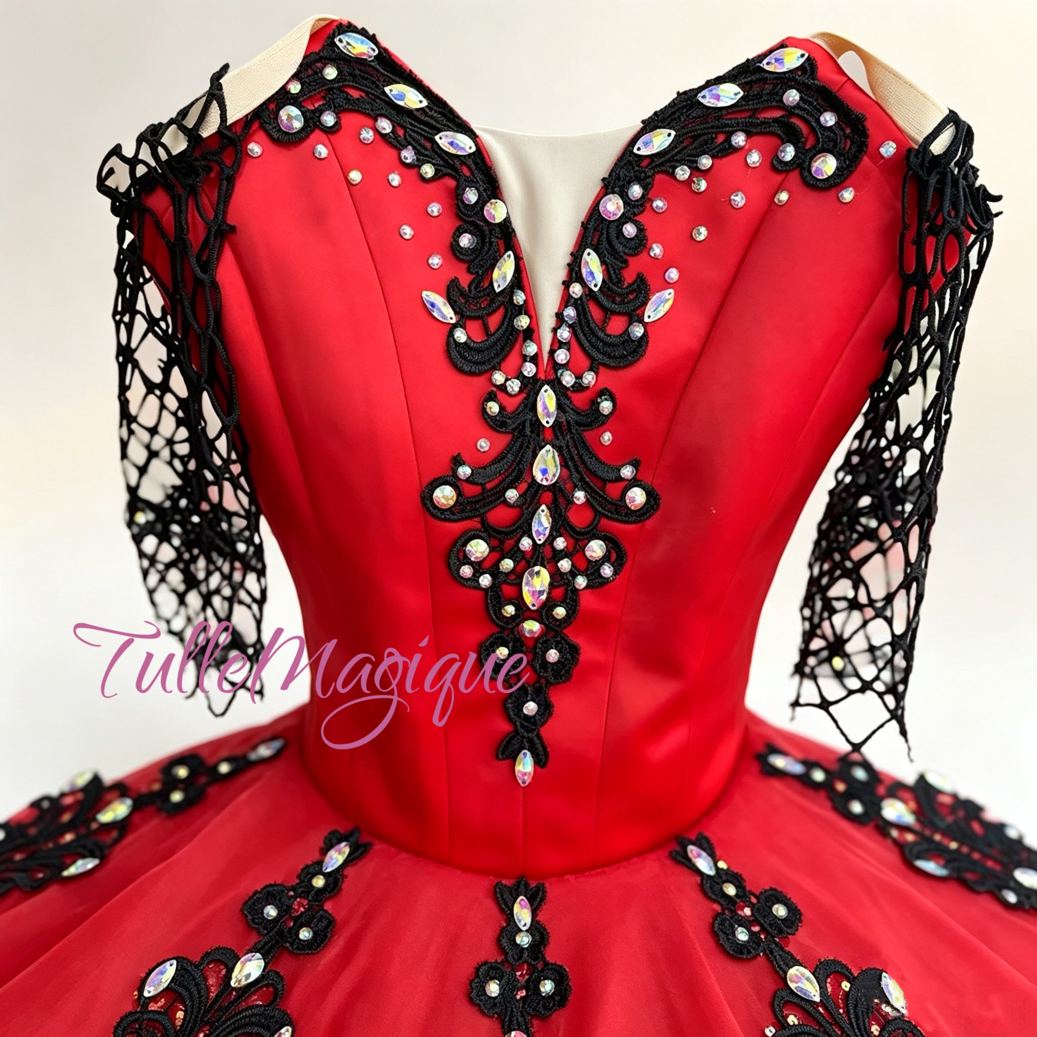 The red satin conflict with the black embroidery on the bodice and intricate black net spanish sleeves are hand-embellished with premium crystals, ensuring you command the audience's attention from the first glissade to your final pose.